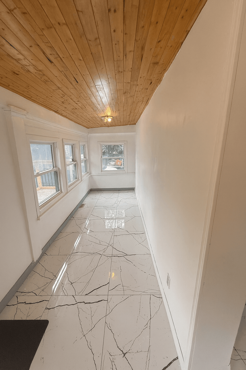 Sunroom with large windows and warm wood ceiling.
